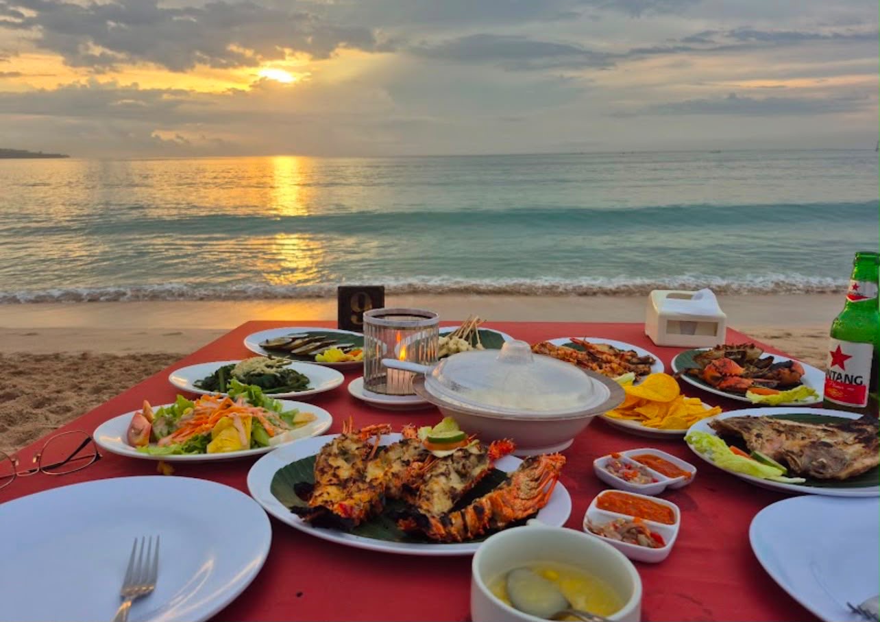 Romantic seafood dinner table on the sand at sunset in Jimbaran Bay